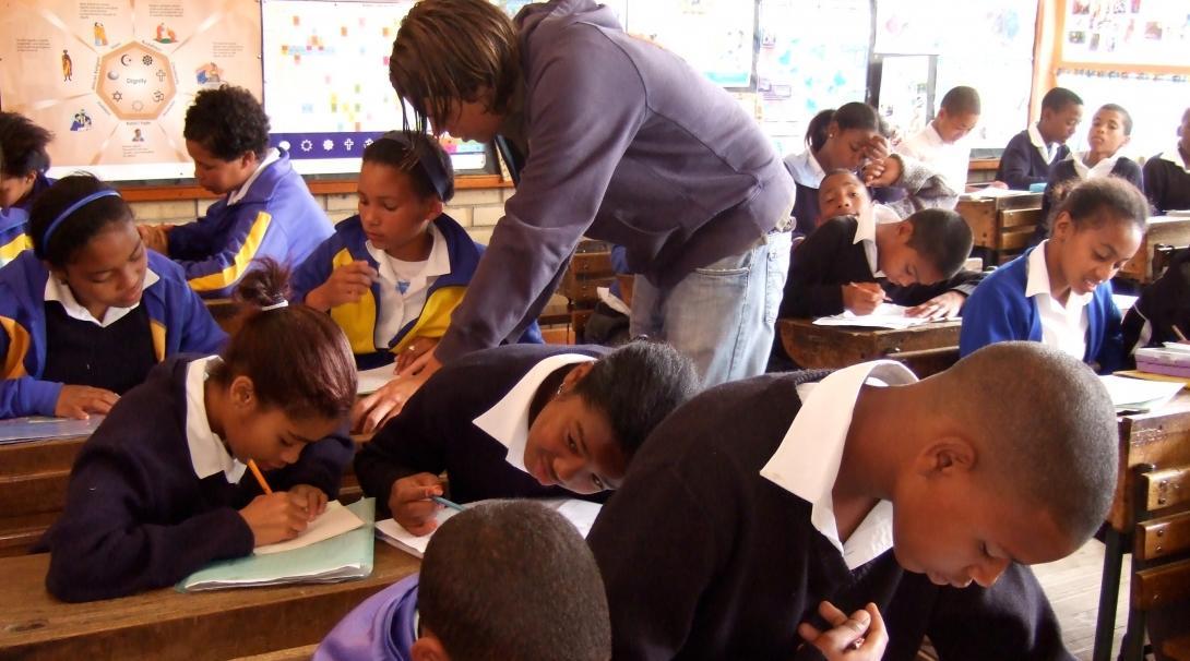 Projects Abroad volunteer working as a teacher in South Africa goes around the classroom to help her students with their classwork Students complete their classroom exercise while a volunteer assists during her teaching work experience in South Africa
